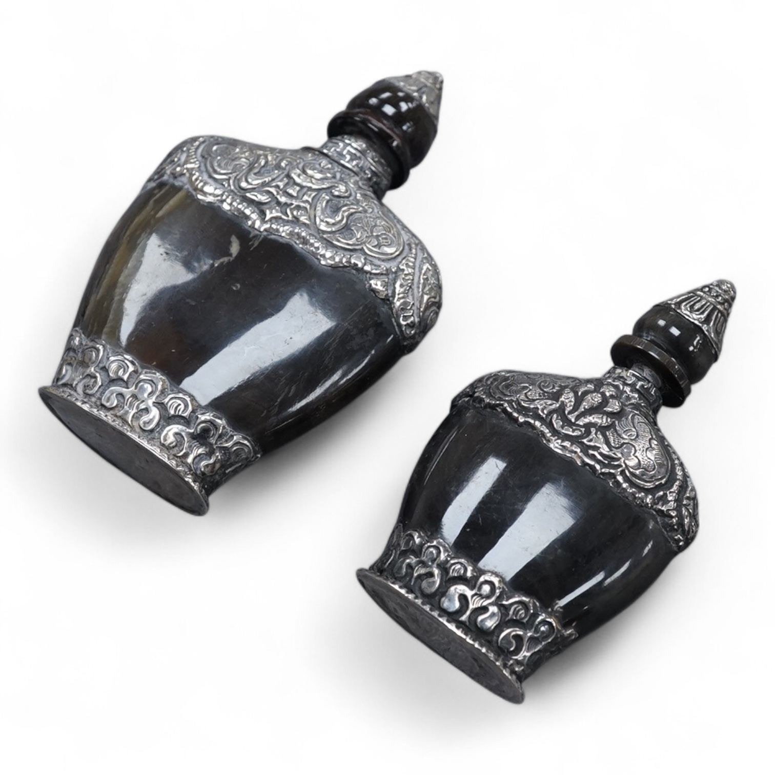 Two late 19th/early 20th century Nepalese embossed white metal mounted horn snuff bottles, largest 87mm.